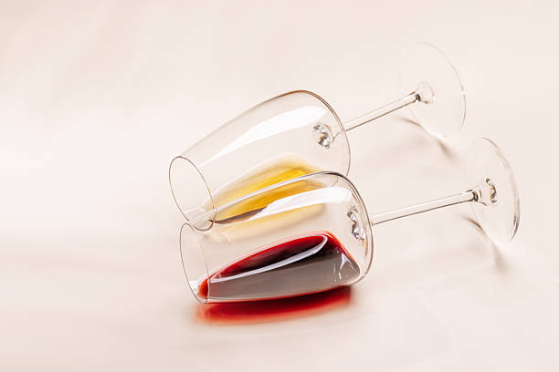 istock Wine glasses with red and white wine lying on beige background 2252307794