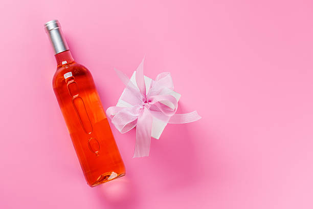 istock Gift box and wine bottle on pink background 2252308295