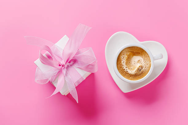 An unrecognizable woman wearing a bathrobe holds hot coffee in a cup with a saucer.