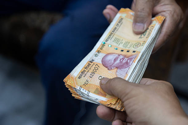 Close-up of hands exchanging Indian 200 rupee notes during a cash payment. Concept shows personal financial transaction, money transfer, everyday economy, and real-life currency exchange in India.