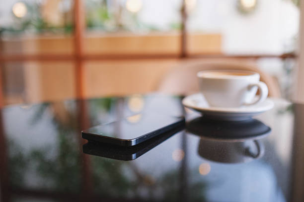 A mobile phone and a coffee cup on the table in cafe