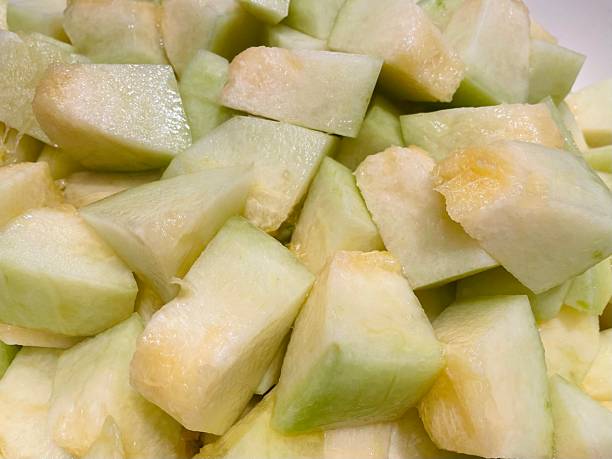 Fresh melon cubes neatly arranged in a bowl, showcasing their vibrant orange and green hues. A refreshing and visually appealing treat, perfect for any occasion.