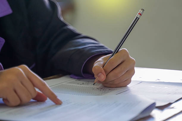 istock Students sitting at desks in a classroom, focused on writing and completing their examination papers or tests during a school lesson. 2252314968