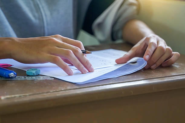 istock High school or university students sitting in a classroom, focused on writing their answers on examination papers during a final test or assessment. 2252314972