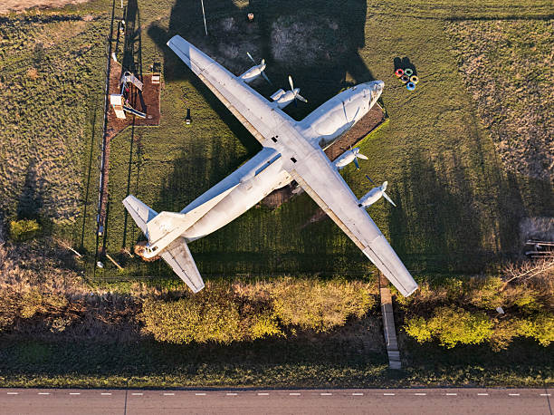 istock High angle aerial view of a large, vintage, four-engine propeller plane abandoned in a grassy field on a sunny day. 2252315519