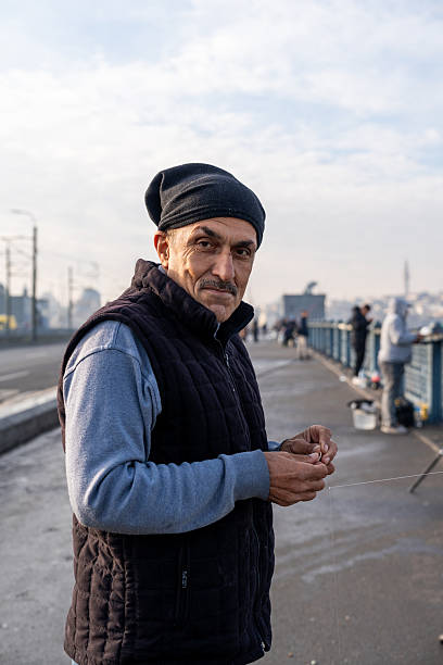 Man holding fishing line, preparing hook on Galata bridge, Istanbul