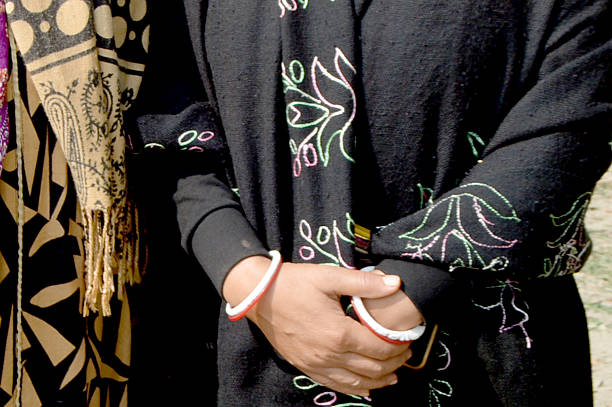 istock A person in a dark, embroidered outfit stands with hands folded, wearing bright bangles. 2252317627