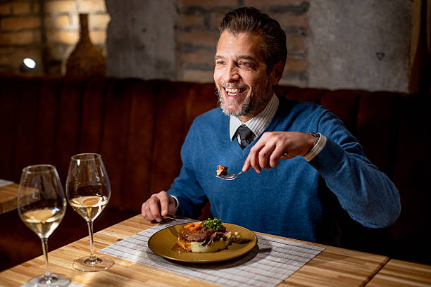 istock Man enjoys dinner at restaurant with wine and food in evening setting 2252318934
