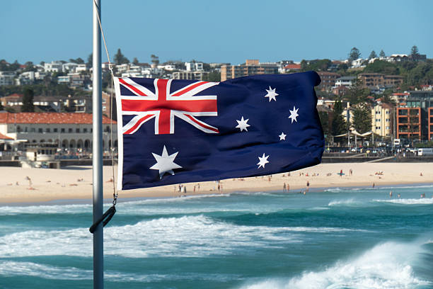 The Australian flag flies at half-mast at Bondi Beach in the eastern suburbs of Sydney because of a nearby terrorist attack on the Jewish community on 14 December 2025. In the left background is the Bondi Pavilion. This image was taken on a hot, windy and sunny afternoon on 17 December 2025.