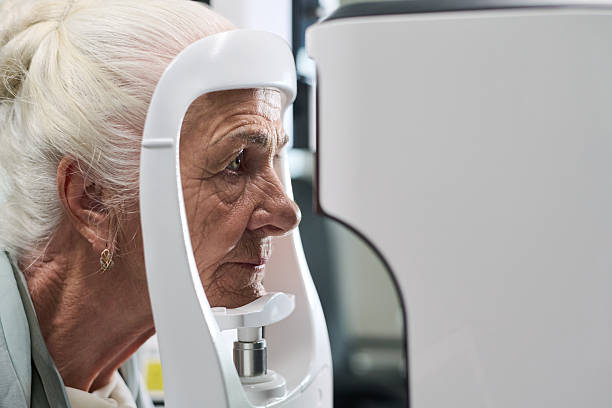 istock Senior Woman Undergoing Vision Screening with Ophthalmology Equipment 2252319320
