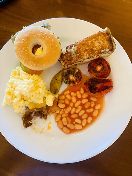 istock A hearty breakfast plate featuring baked beans, mashed potatoes, baked tomato, and a bagel bun, representing a wholesome and satisfying morning meal. 2252323834