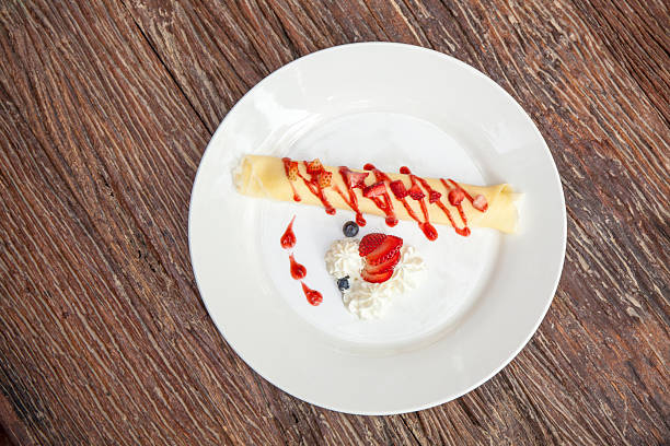 Close-Up Of Dessert Garnished With Strawberries And Mint Leaves Served In Plate