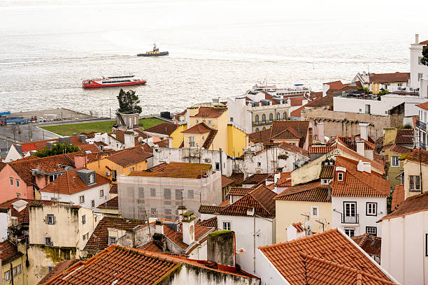 Lisbon Portugal December 05 2025. Historic rooftops frame multiple ferries moving across the Tagus River near the Lisbon waterfront.