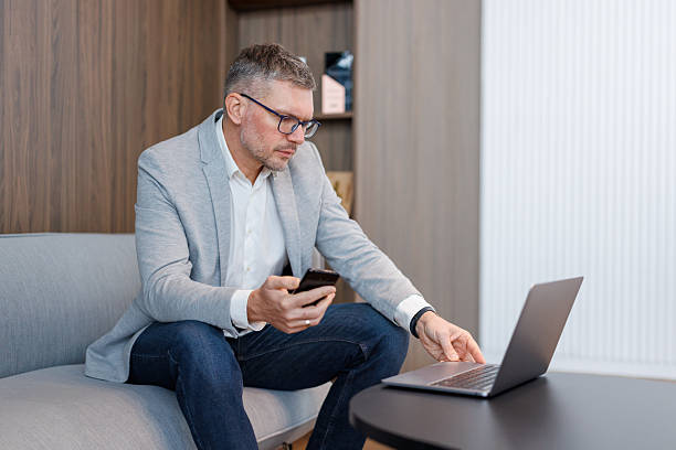 istock Businessman multitasking with mobile phone and laptop in modern office 2252328350