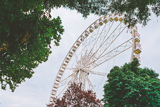 istock Large white Ferris wheel rising above lush green trees 2252329959