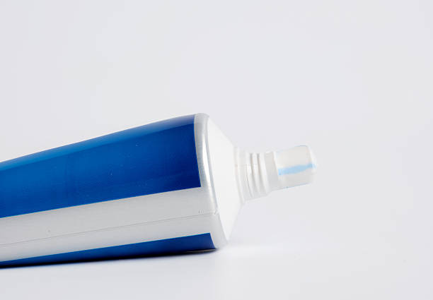 An unrecognizable woman putting toothpaste on a toothbrush in the bathroom in the morning