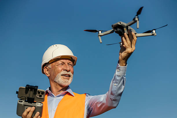 istock Senior male environmentalist in orange vest operating drone outdoors under clear blue sky 2252339427
