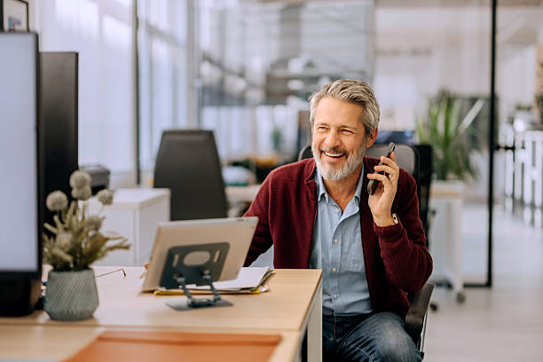 istock Cheerful mature businessman talking on smart phone while working at the office 2252343583