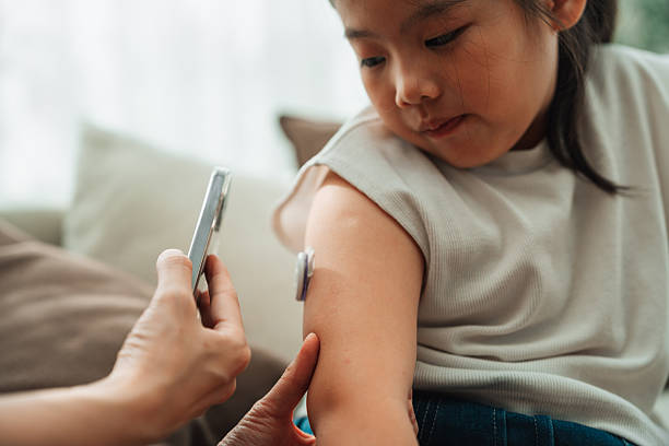 istock Modern mom using CGM device to check her daughter's blood sugar level 2252346938
