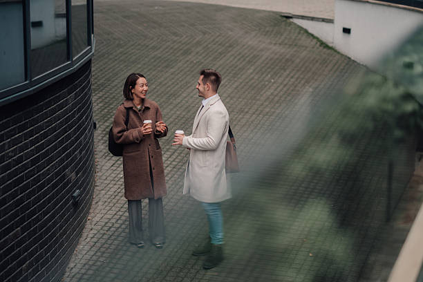istock Colleagues smiling talking during coffee break outside office 2252352128