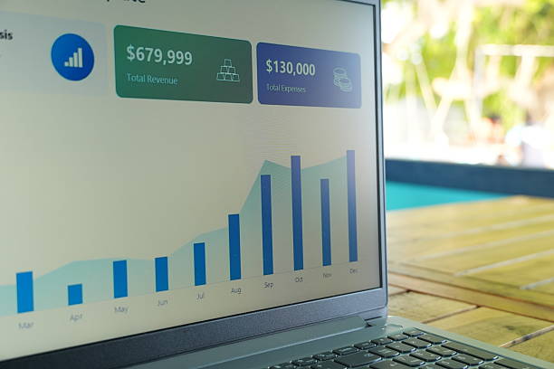 Laptop showing financial growth chart on outdoor table by pool side