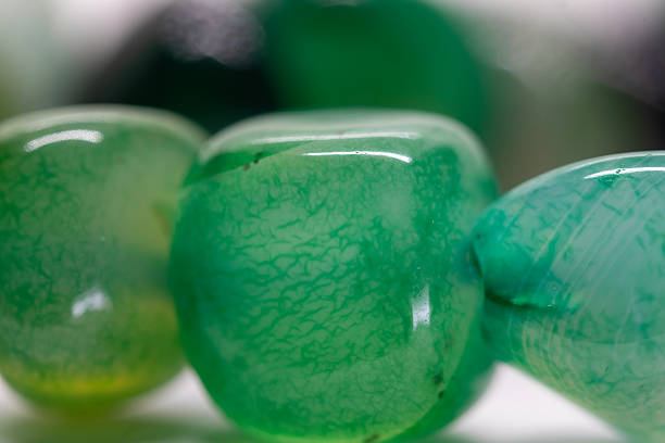 Hand of an unrecognizable female is about to wear an emerald ring.