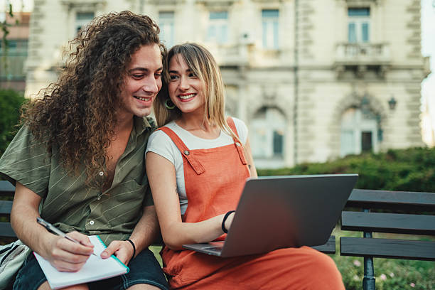 istock Young adult students studying together outdoors with laptop 2252352639
