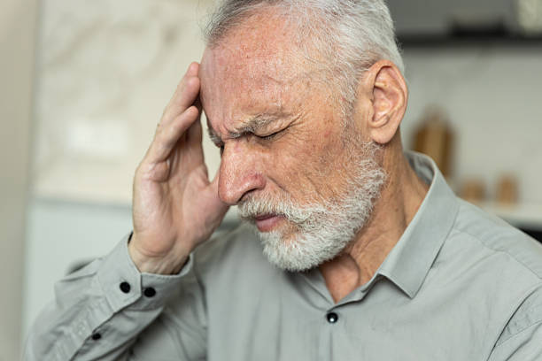 istock Elderly man experiencing headache in a home living room setting 2252352789