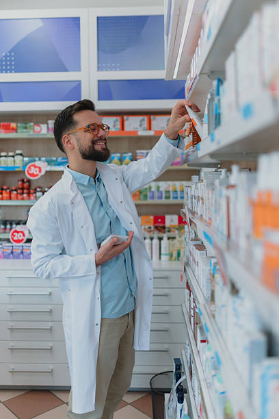 istock Pharmacist smiling while arranging medicine on pharmacy shelves 2252355828