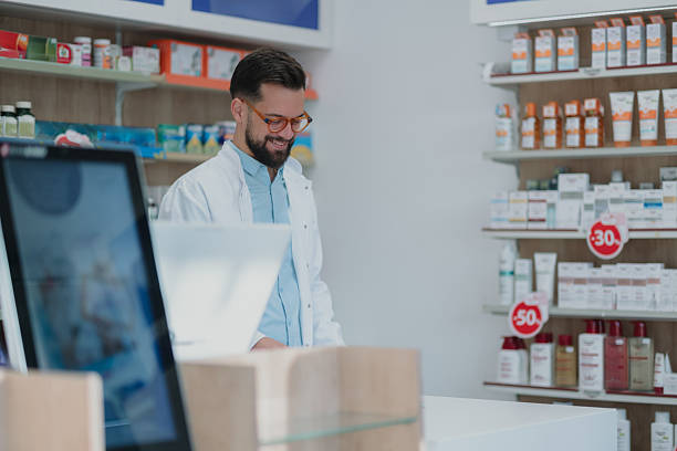 istock Smiling pharmacist working at pharmacy counter with medicine 2252355844