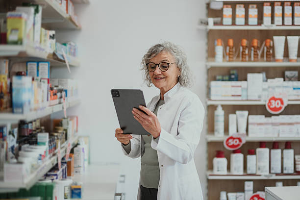 istock Senior pharmacist checking inventory with digital tablet in pharmacy 2252355979
