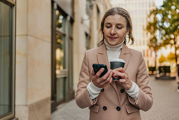istock Adult woman enjoys coffee while using phone in Berlin's lively urban setting during a sunny day 2252356191
