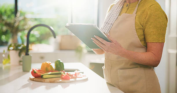istock Senior, woman and hands with tablet for online cooking tutorial or healthy recipe in kitchen. Elderly, female person or research with technology or ingredients for natural organic food or meal prep 2252357267