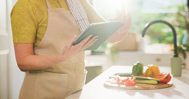 istock Elderly, woman and hands with tablet for online cooking tutorial or healthy recipe in kitchen. Senior, female person or research with technology or ingredients for natural organic food or meal prep 2252357269