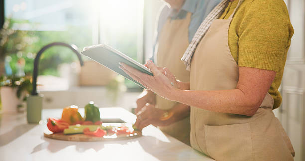 istock Couple, hands or tablet with online cooking tutorial for healthy recipe or tips in kitchen. Apron, man and woman with tech, ingredients or research for diet, natural organic food or meal prep in home 2252357275