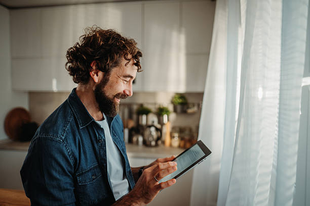 istock Man smiling reading tablet content at home 2252357738