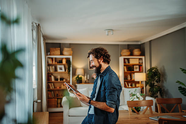 istock Man smiling using digital tablet in living room 2252357748