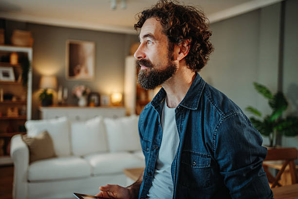 istock Man relaxing in living room using digital tablet 2252357765