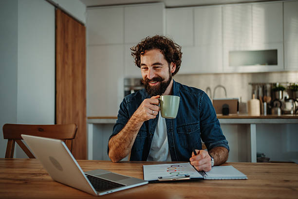 istock Man drinking coffee working from home on laptop 2252357859