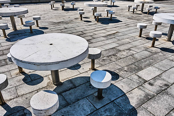 Picture of an empty terrace in as street, used by a cafe bar and restaurant with nobody seating on wooden chairs and tables. This image depicts a row of empty chairs and tables set up outside a cafe or bar in Belgrade, Serbia. The scene is characterized by a sense of calm and tranquility, as the outdoor seating awaits patrons. The vintage-style metal furniture, placed along the sidewalk, adds to the cozy, inviting atmosphere typical of many European cafes. The empty setting suggests a moment of quiet before the bustle of customers, capturing the serene side of urban life in the Balkan region.