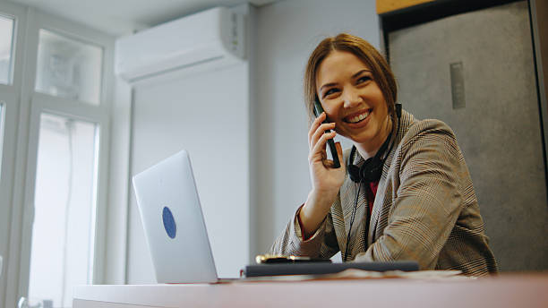istock Woman in a professional setting confidently talking on the phone while smiling at her laptop 2252362329