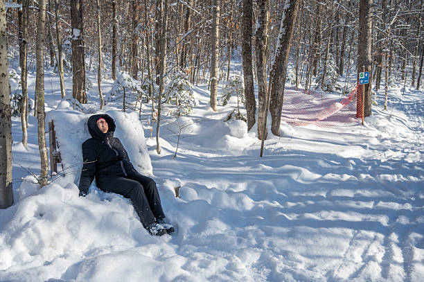 Woman resting on bench in footpath in Quebec city during a day of winter with snow