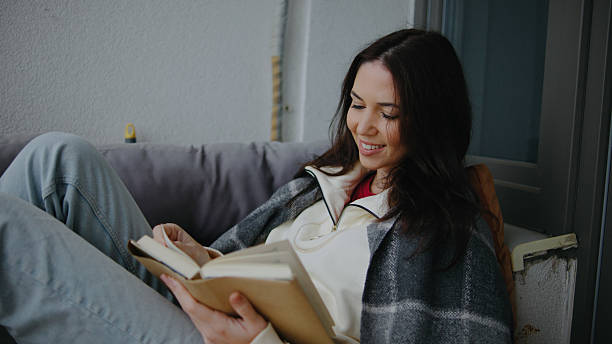 istock Woman reading a book comfortably while sitting on a cozy sofa in a bright indoor space during daytime 2252362800
