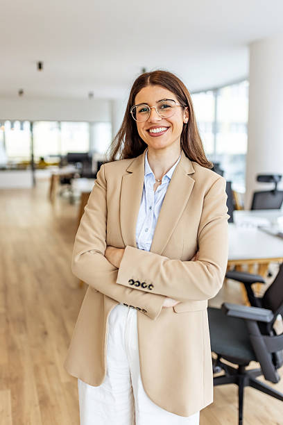 istock Confident Business Woman In Beige Blazer Smiling In Modern Open-Plan Office 2252365232