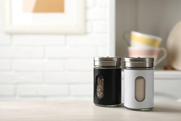 istock Salt and pepper shakers on light wooden table in kitchen, closeup. Space for text 2252365249