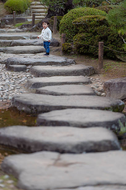 Little boy standing on stones in public park
