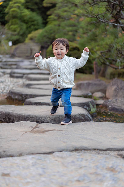 Little boy walking on stones in public park