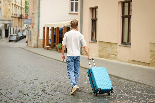 istock Goodbye. Man with luggage walking outdoors, back view 2252367267