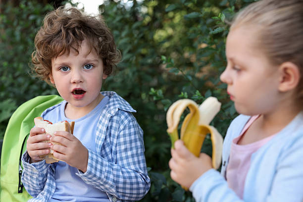 Cute kids eating food outdoors. School lunch