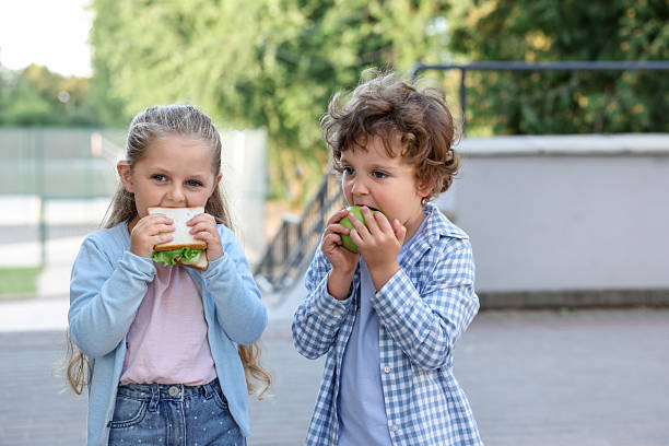 istock Cute kids eating food outdoors. School lunch 2252367896
